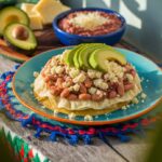 A classic Honduran baleada with beans, cheese, and avocado, served on a rustic wooden table with traditional decor.