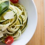 A bowl of freshly cooked zucchini noodles garnished with basil and Parmesan, a delicious low-carb pasta option.